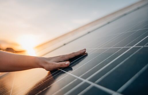Eine Hand streicht über eine Photovoltaik-Modul.