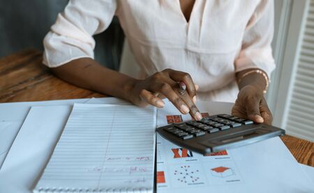 Schwarze Frau tippt etwas in den Taschenrechner